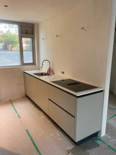 Moderne keuken met een wastafel en kookplaat, in een onafgebouwde ruimte.