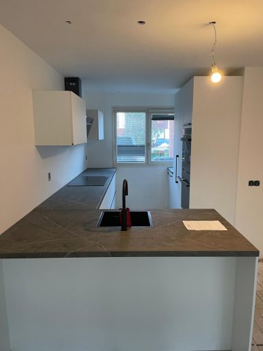 Moderne keuken met een betonnen aanrechtblad en witte kastjes.