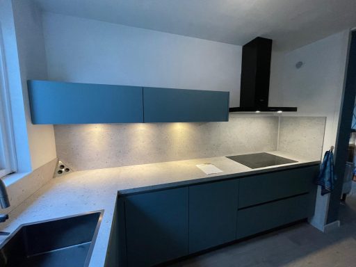 Moderne keuken met groene kastjes, een werkblad, en ingebouwde kookplaat.